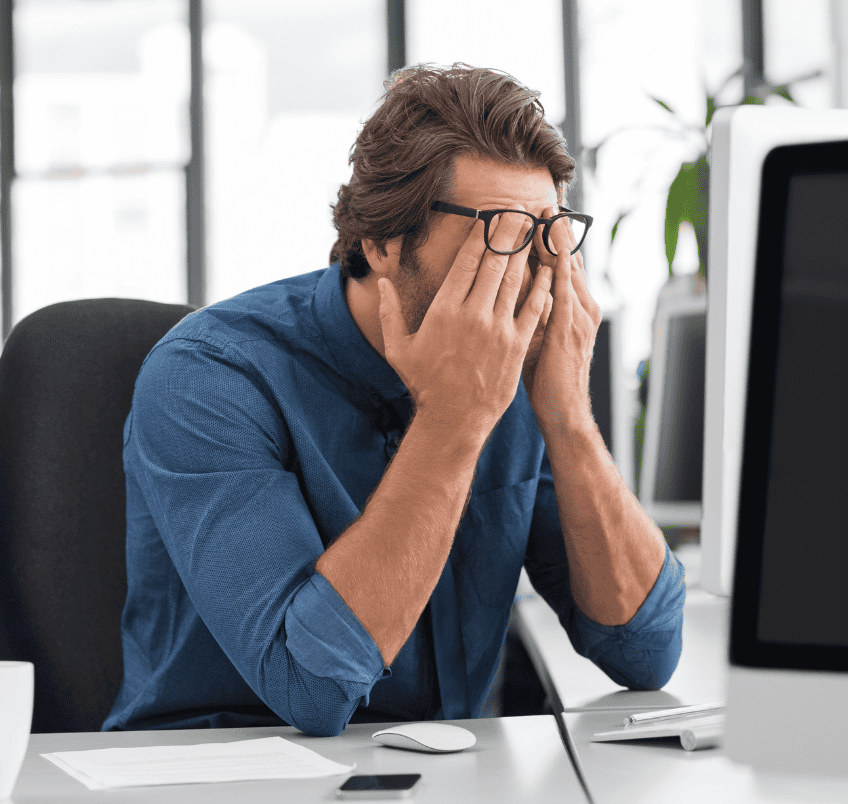 http://Tired%20man%20holding%20head%20at%20his%20office%20desk