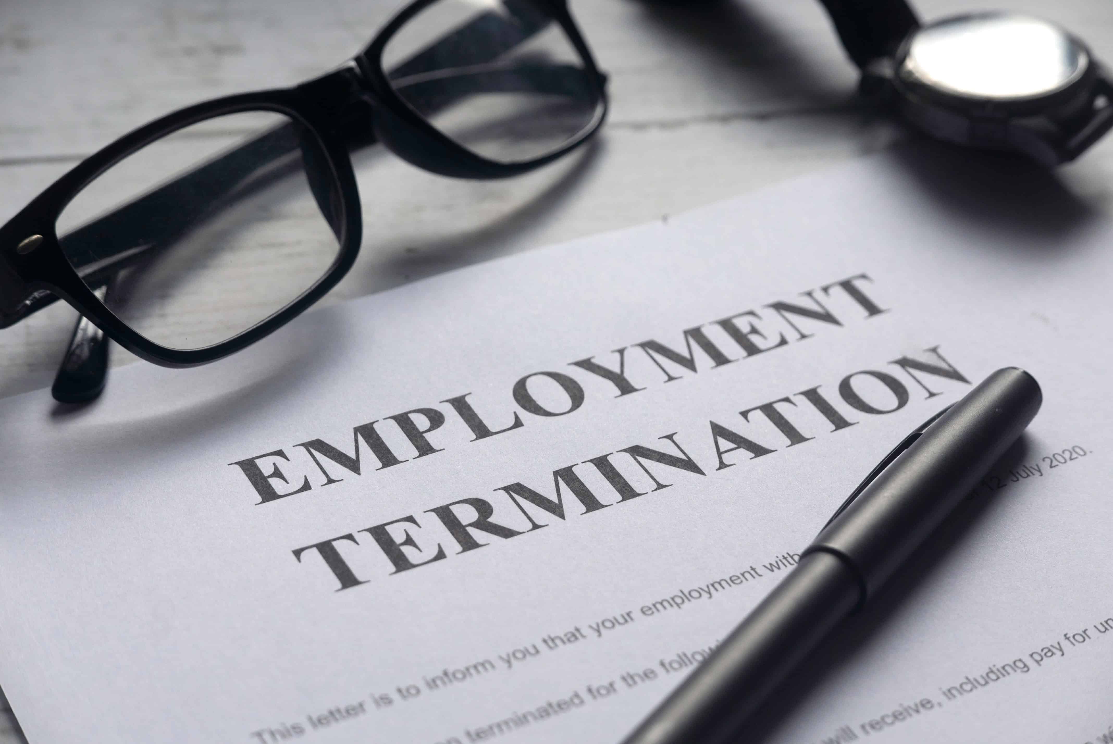 Employment termination contract on a desk with black glasses on top and a black pen